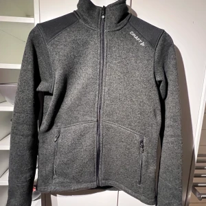 Craft Noble Zip, strl S - Craft Noble Zip fleece; tjockare/kraftigare fleecejacka med blixtlås hela vägen. Mörkgrå, strl S. Obetydligt använd, mycket bra skick. Frakt betalas av köparen.