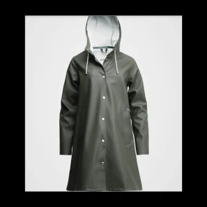 Regnjacka  - Mosebacke  green StutterheimStockholm är en klassisk ofodrad regnjacka, inspirerad av Alexander Stutterheims morfars gamla regnrock. Den är handgjord i Rubberized Cotton, med  Mosebacke greendubbelsvetsade sömmar för full vattentäthet. Helt nytt oöpnad. 