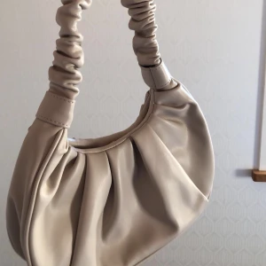 Beige axelväska  - Säljer denna väska jag aldrig använt då den inte riktigt är min stil. Priset kan alltid diskuteras. 