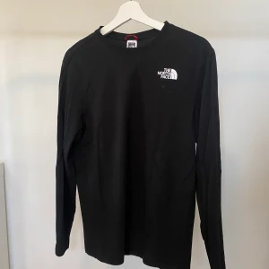 The North Face tröja, storlek S - Svart The North Face långärmad t-shirt med tryck på baksidan. Nyskick, använd max 5 gånger.