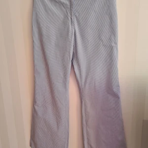 Day Birger et Mikkelsen Byxor randiga strl 42 - Byxor med blå och vita ränder från Day Birger et Mikkelsen. Strl 42. Med tillhörande (avtagbart) rött midjeband. Bakficka. Gylf. Tvättade men aldrig använda. Midja: ca 88 cm. Innerbensmått: ca 83,5 cm.