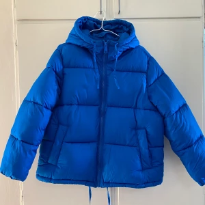 Pufferjacka med huva från H&M - Jättefin kornblå pufferjacka med huva från H&M. Storlek M. Sista bilden visar passformen fast i en annan färg. 