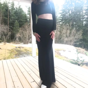 Balklänning  - Balklänning i två delar från Nelly. Stretchigt material med smyckedetaljer vid hals och ärmar. Använd en gång. Storleken är 40 och är själv 175 cm och funkar med 7 cm klackar. 