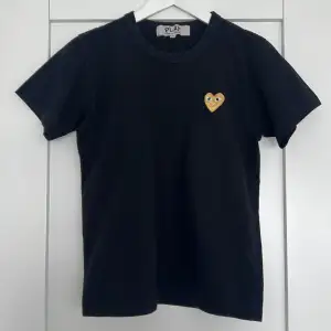 En T-shirt ifrån Comme des Garçons PLAY. Storlek M men liten i storlek så passar även en XS/S.  Sparsamt använd och i fint skick.