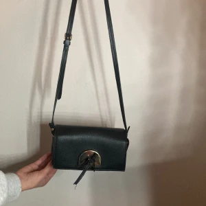 Gamall Chanel väska från 1980  - Svart liten bärbar väska med små guld ditaljer och en roset