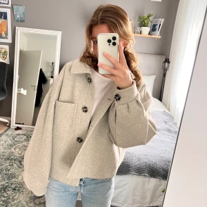 Kort grå kappa - Slutsåld jacka i ullblandning från NA-KD. Jackan har en oversized fit och är inte stickig då den har foder innuti. Jackan användes under våren så den är lite nopprig men det syns knappt! Orginalpris är 879kr🫶