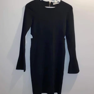 Stickad klänning  - Säljer min klänning med volang i ärmarna, dragkedja baktill och öppningar på sidorna