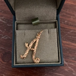 Maria Nilsdotter hänge A  - Gulplätterat A poetic letter från Maria Nilsdotter. Helt nytt och oanvänt. Ca 3 cm med ögla.  Äkta silver. ASK INGÅR EJ. 