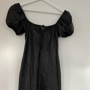 Skinnklänning med puffärmar  - Assnygg kort ”skinn” klänning med detaljer på bröstet. Tight i modellen och sitter som en smäck. Prislapp kvar