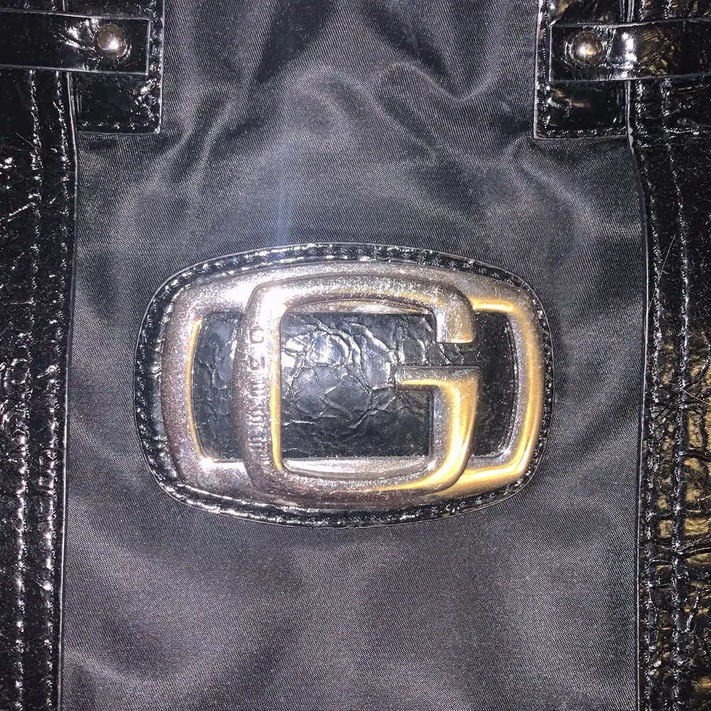 en handväska från guess köpt secondhand i färgen svart. Väskor.