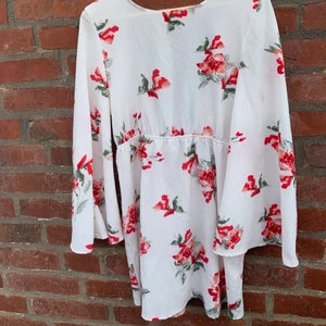 Perfekt midsommarklänning - En vit/röd blommig klänning från Pretty Little Thing i storlek 10. Perfekt för midsommar eller alla andra härliga sommardagar. Väldigt sval och skön med breda armar. Öppen i ryggen som stängs med knyten.