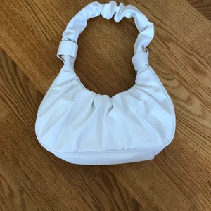 Axelremsväska  - Säljer denna helt nya vita axelremsväska med ett tillhörande långt band. Frakt tillkommer