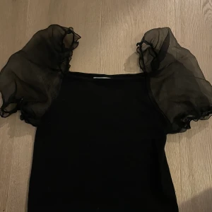 Svart topp - Säljer denna super gulliga topp i ribbat svart material med genomskinliga armar som har skimmer i sig. Denna gulliga topp säljer jag för 50 kronor + frakt 