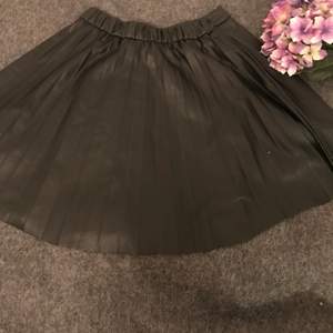 En svart plisserad kjol som har används 2 gånger passar till allt 