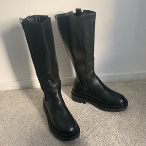 Höga Chelsea boots - Säljer ett par helt oanvända Chelsea boots med högt skaft och tjockare sula. Dom är i strl 40 men känns som 39. Skorna är höga och slutar ca 10 cm under mina knän. Jättesnygga och bekväma! 