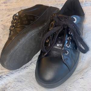 Detta är ett par svarta Guess skor som använts ett par gånger och är för det mesta bara smutsiga vilket kan tas bort snabbt. Det speciella med dessa skorna är de silvriga detaljerna och hur skorna både har en matt och en mer glansig del. Dessa är perfekt till den där hel svarta outfiten eller bara till din favorit look! Dem är köpta från UK. STÅR EJ FÖR FRAKT.