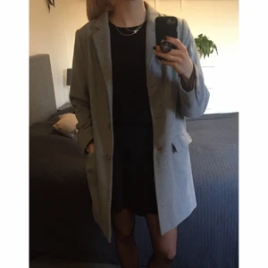 Grå kappa - Ljusgrå kappa med två fickor, krage, slag och knappar mitt fram. Inga krusiduller på ryggen. Märkt storlek 44, men upplevs som en 40. Jag har vanligtvis 38 men kan ha en tjockare tröja under den här kappan🦫🌿 