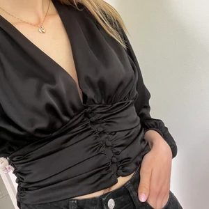 Svart satinblus - Säljer en svart satinblus från Ginatricot endast använd enstaka gånger. Så gott som ny, riktig festtopp 💫 Knappar i mitten, slutar vid naveln, balongärmar. Storlek S/36