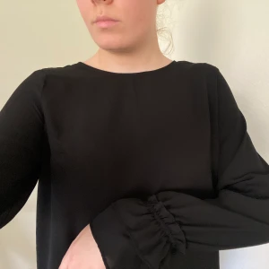 Svart blus - En svart enkel blus med volanger vid handlederna! Har använt denna blus mycket då den varit en favorit i garderoben. Fint skick💙