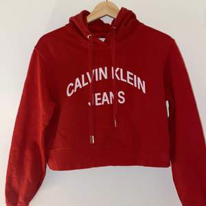 En röd croppad hoodie från Calvin Klein storlek xs kommer inte till användning längre är i ett gott skick ordinarie pris 999kr säljes för 350kr