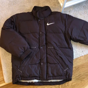 Nike jacka - Brun Nike vinterjacka i strl. XS, sitter som en S/M beroende på hur ”oversized” man vill ha den. Finns dragsko längst ned.
