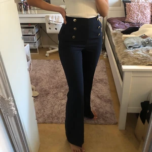 Marinblåa kostymbyxor - Ett par marinblåa kostymbyxor med guldknappar, köpt från h&m. Storlek S/36. Aldrig använda, alltså som nya. Sitter som ett smäck. Jag är 165 cm