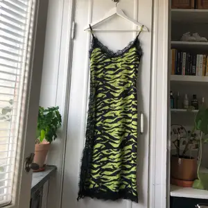 Helt oanvänd midi klänning från New Girl Order!  •Storlek: UK 8/36 (liten i storleken) •Slitslängd: 27 cm •Färg: Grön med svarta ”ränder” och svart spets längst kanterna 