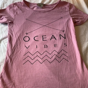 Ocean vines t-shirt - En rosa tröja med en text där det står ”ocean vibes” på i svart text. Skönt material och ett mönster under texten. frakt ingår. Tvättar såklart innan frakt. 