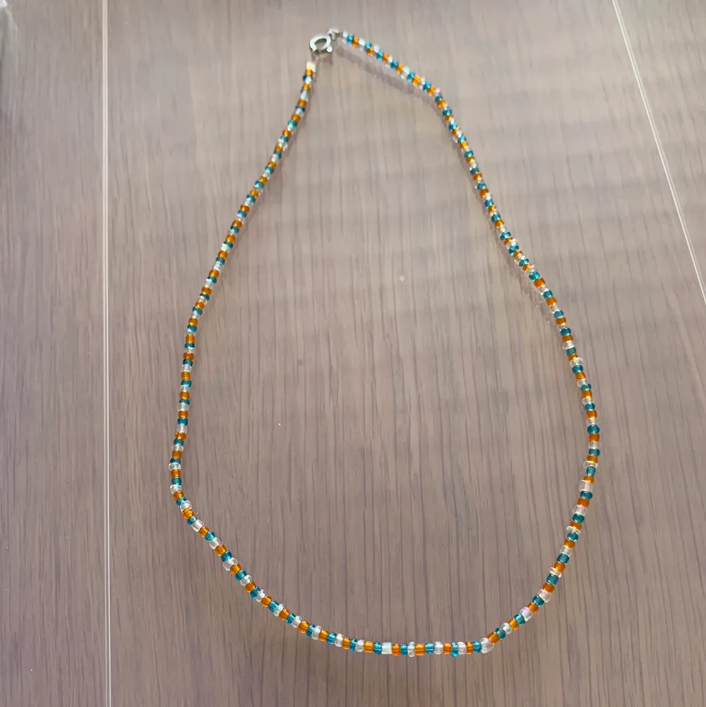 Vitt, oranget och blått pärlhalsband med små pärlor 🤍🦋🧡 49kr + 13kr frakt . Accessoarer.