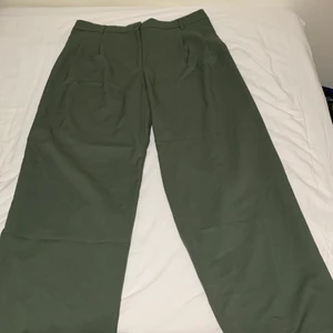 Kostymbyxor från Monki - Supersnygga mörkgröna kostymbyxor från Monki med  raka ben, dessa har när jag provat dem släpat i marken och jag är 175 cm lång. De är aldrig använda, endast provade och är i nyskick! På baksidan av byxorna finns det två fake fickor. Du betalar priset (260kr)+frakten. 