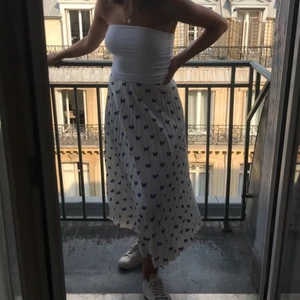 Plisserad kjol Other stories  - Säljer denna jättevackra kjol från Other Stories. Den är vit med kornblå fjärilar. Den har knäppning med dragkedja på sidan. Den går till mitten på vaderna. Storlek 34