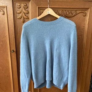 COS tröja i ullblandning, stl S - Fantastisk tröja från COS, rosettliknande detalj på baksidan. Stl S. 45 % ull, 29 % polyamid, 23 % mohair, 3 % elastan. Kanske någon enstaka noppa som går lätt att plocka bort.