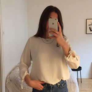 Vit långärmad blus - Vit långärmad blus i tunt tyg. Längst ned på ärmarna är det snittat av den anledningen att dem ska knytas.