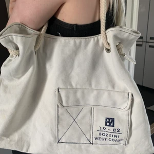 Vit tygväska - Vit tygväska som är köpt på secondhand, nypris 100kr, säljer pga att den aldrig kommer till användning, finns en ficka med dragkedja.