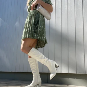 Vita stövlar  - Snygga vita stövlar med klack, i jättebra skick då de knappt är använda. Skorna är i storlek 40 men passar bättre för dem med storlek 39. (Klänningen på bilden säljs också)