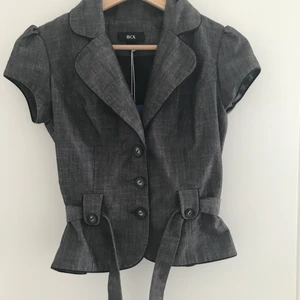 Grå väst  -  En grå väst med skärp och knappar. Snygg som fest topp 