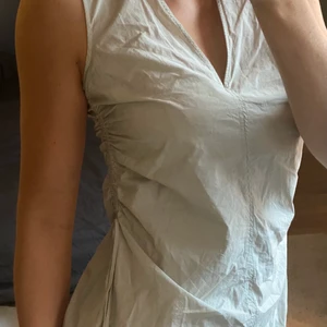 Klänning COS - Klänning i prassligt och tunnt bomullsmaterial från COS! Köpt förra sommaren och använd en enda gång. Snygg snörningsdetalj på sidorna som det går att justera passformen med. Längden är på mig som är 173 till strax ovanför knäna! Färgen är ljust grå/grön