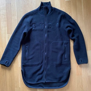 Svart Svea piléjacka strl M  - Helt ny oanvänd svart jacka i pilé. Lång modell med fickor och dragkedja. 