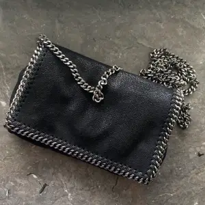 Stella McCartney crossbody i svart. Finns inte kvar på hemsidan. Aldrig kommit till användning! Nypris ca 7000kr. Äkta! Köptes på Stella McCartney i Stockholm när nått år sedan.☺️