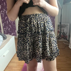 Gullig marinblå/svart blommig kjol från Shein strl XS - Super gullig marinblå/svart kjol med vit/gula blommor från Shein i storlek Xs. Man kan knyta den därfram och passar perfekt till våren och sommaren. Använd endas få tal gånger. 