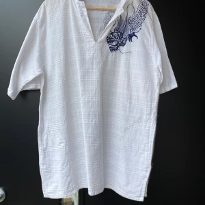 Kortärmad skjorta - Snygg oversize skjorta med broderad drake på. Strl oklar. XS-L beroende på hur den ska sitta.