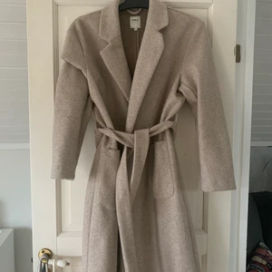 Beige Kappa från Only strl S - Jättefin beige kappa från Only! Strl S. Har 2 stora fickor och band runt midjan. Är 170 lång och kappan slutan ungefär vid knäna. Frakt ingår i priset.