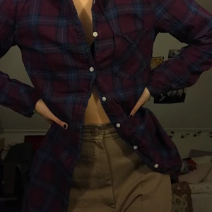 flanellskjorta  - lila och blå rutig skjorta som är lite längre i modellen. 