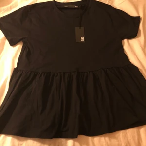 T-shirt - En svart T-shirt med volang grej längst ner! Köpt för 100 kr på Lager 157. Helt ny och ändats testad! Prislappen sitter kvar. Storlek XS men jag skulle nog säga att den är stor i storleken så skulle nog passa en S eller kanske M💕Köparen står för frakten. Hör av dig om du är intresserad! 