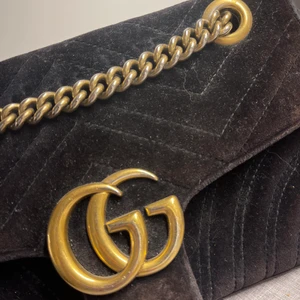 Gucci marmont velvet black  - Gucci Marmontväska i svart sammet.  Inköpt på mytheresa -18. Kvitto finns. Inredning i rosa tyg. Hårdvara i guldmetall. I andvänt skick: Fodret är smutsigt med gammalt svart lim i innerfickan samt bleknad färg i fodret. Utsidan är något missfärgad (solskadad) fler bilder kan skickas på begäran.   Mått Bredd: 21cm, Höjd: 14cm, Djup: 6cm, Axelrem: 113cm Tillbehör: ingen dustbag eller kartong medföljer. Endast väska. 