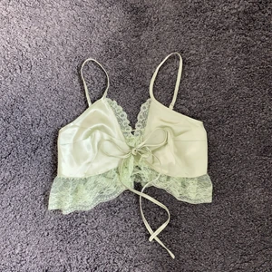 Silkeslinne  - Ljusgrönt superfint silkeslinne med knytning framtill. Har volang med spets nertill och justerbara axelband. Säljes för kommer inte till användning.