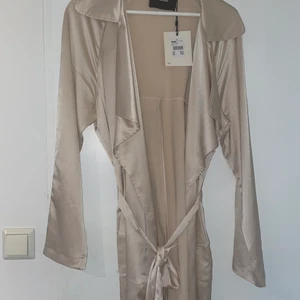 Oanvönd silkesguldig kimono storlek L - Helt oanvönd, (prislapp fortfarande kvar) från bikbok. Perfekt kvalite och jätteskön på. Säljer då jag köpte fel storlek.