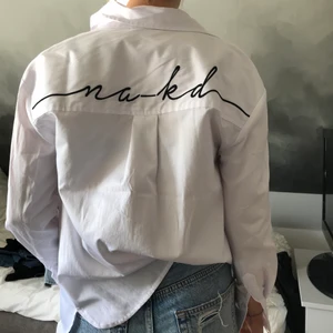 Vit NA-KD skjorta - Vit NA-KD skjorta med tryck i ryggen. Knappt använd så väldigt bra skick! Storlek 34 men ganska stor i storlek. 