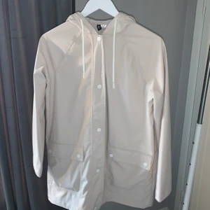 Regnjacka från H&M storlek S - Ljus Regnjacka från H&M som jag köpte för ungefär 1 år sedan. Bara använd en gång. Jackan stängs med knappar.  Fraktas inte
