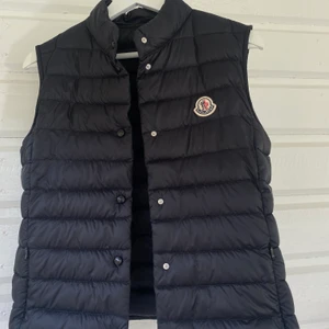 Moncler-väst i modellen ”Liane” i strl 1 - Säljer min svarta Moncler-väst i modellen ”Liane” i storlek 1 (motsvarar S) Säljer pga använder den aldrig och därav väldigt bra skick! Den är köpt på NK, kvitto finns! Säljer för 3500kr Hör av dig om du är intresserad!